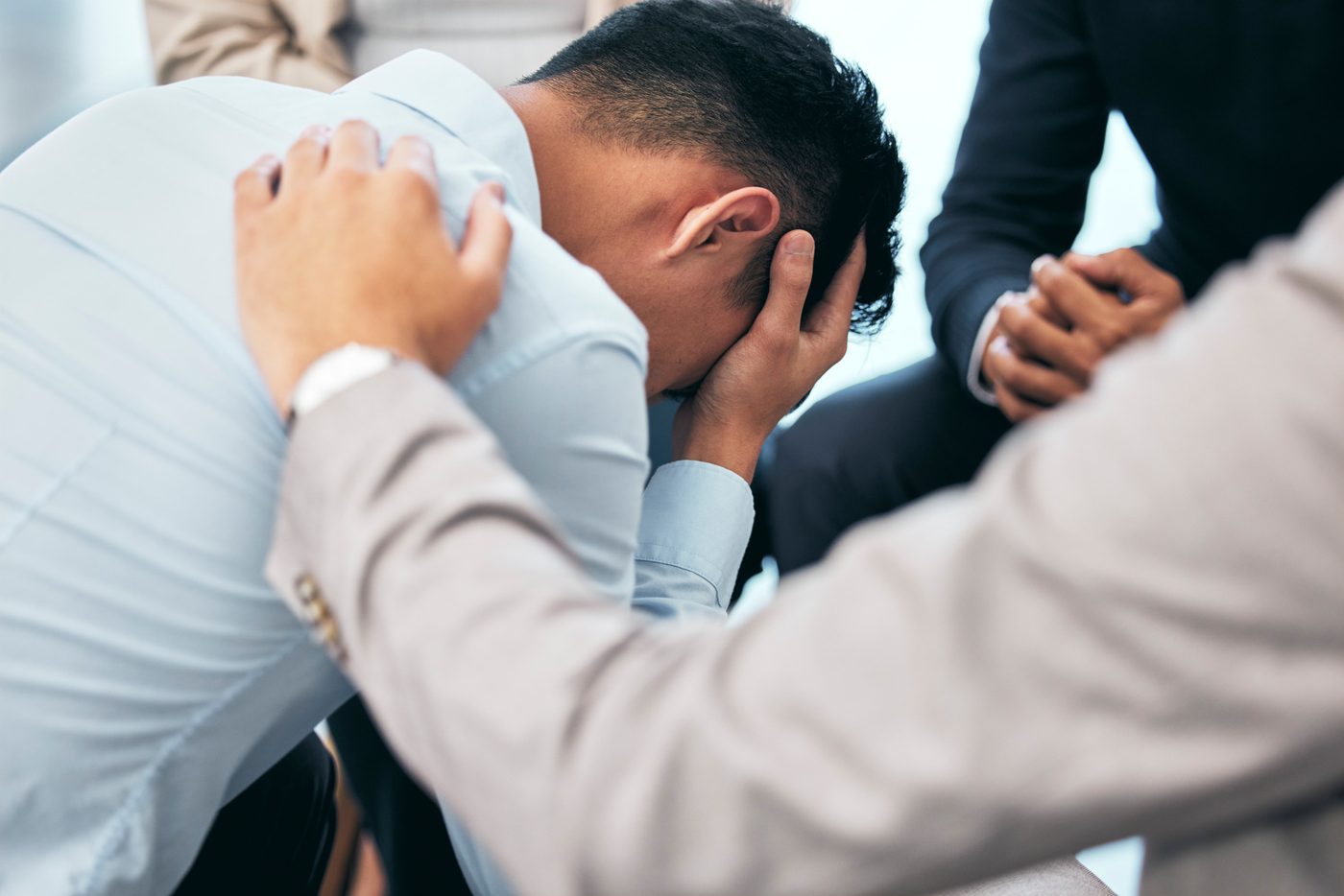A distressed man being comforted by a colleague